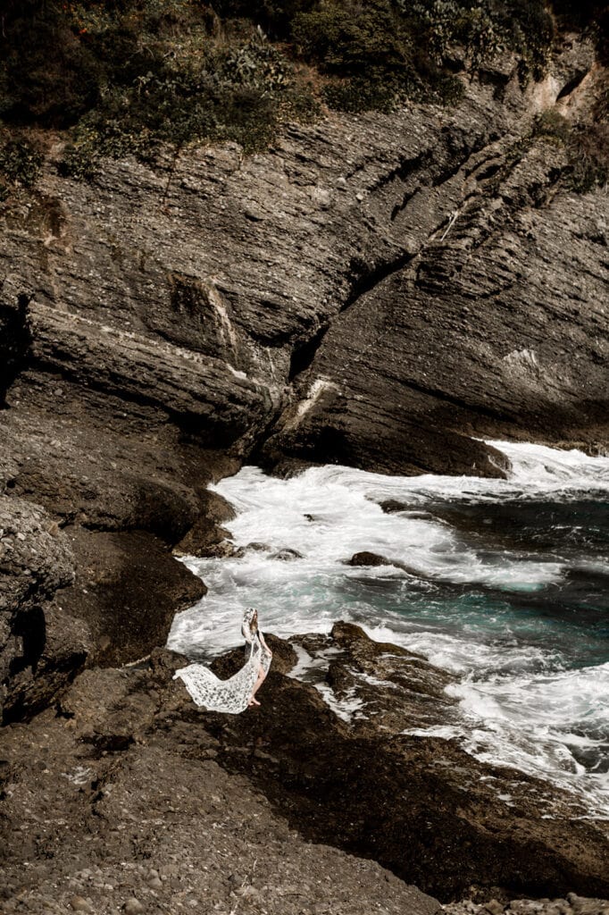 Woman on rocky shoreline of Punta Chiappa Portofino Italy