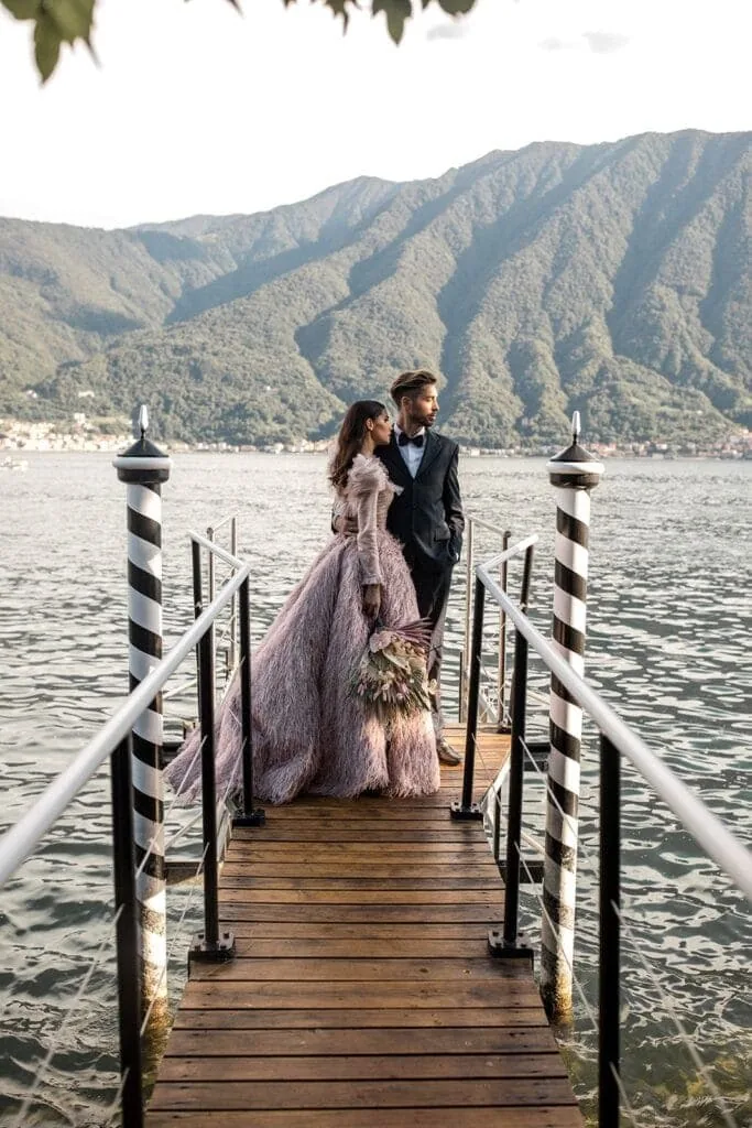Bride and groom pose for portrait on a dock in Lake Como after their wedding