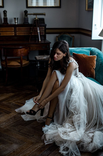 Bride gets ready before wedding ceremony and puts on designer bridal heels