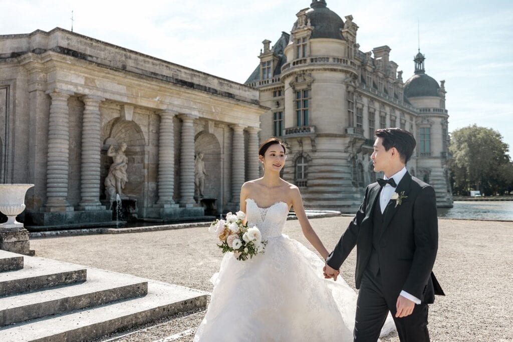 Bride and groom walking at Chateau de Chantilly in France