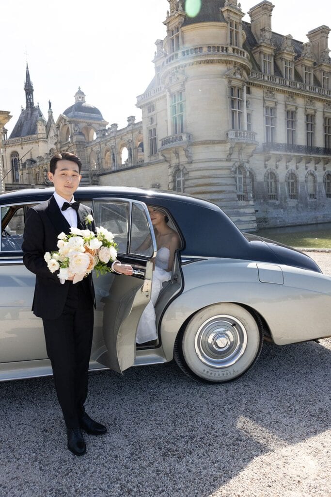 Groom opens door of vintage Rolls Royce for bride