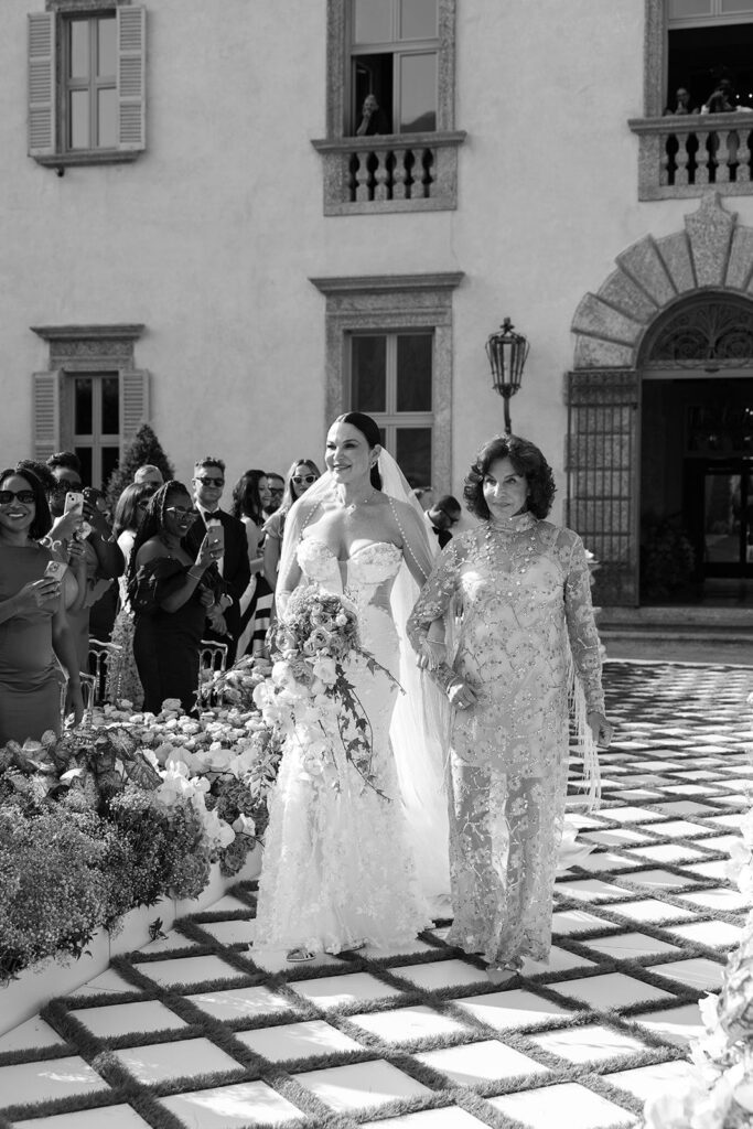 Bride and mother of the bride walk down wedding ceremony aisle