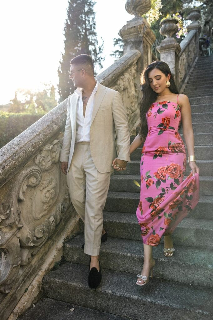 Man and woman walking stairs at Villa Monastero while Lake Como engagement photographer takes portrait