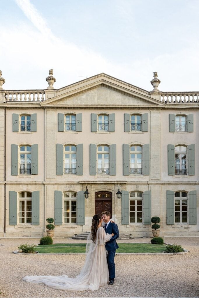 Bride and groom embrace in front of Chateau Tourreau