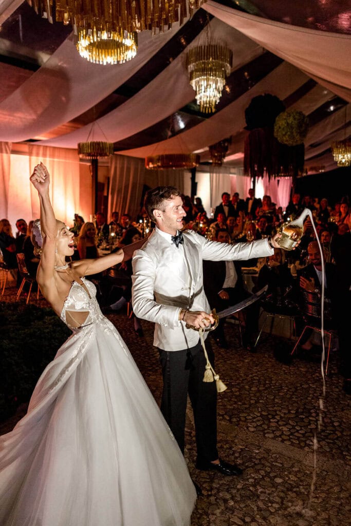 Wedding couple's sabre opening of champagne instead of traditional wedding cake, photo by Lilly Red